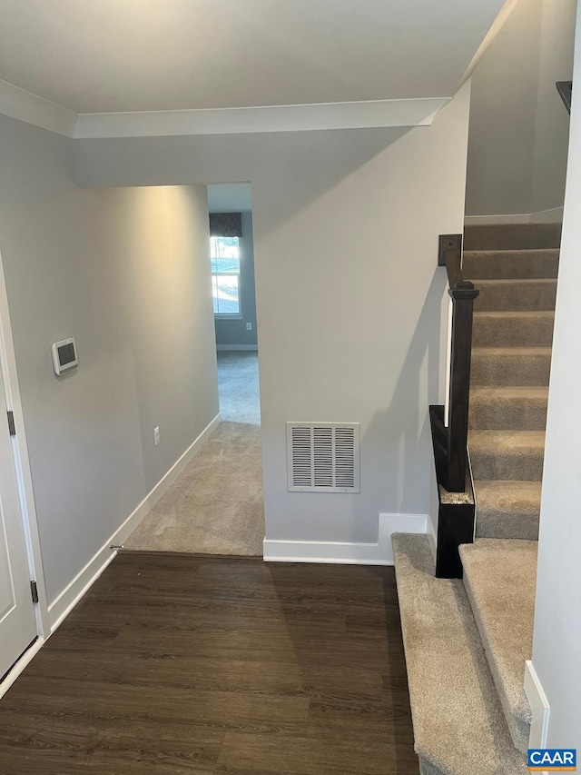 stairway featuring wood finished floors, visible vents, and baseboards