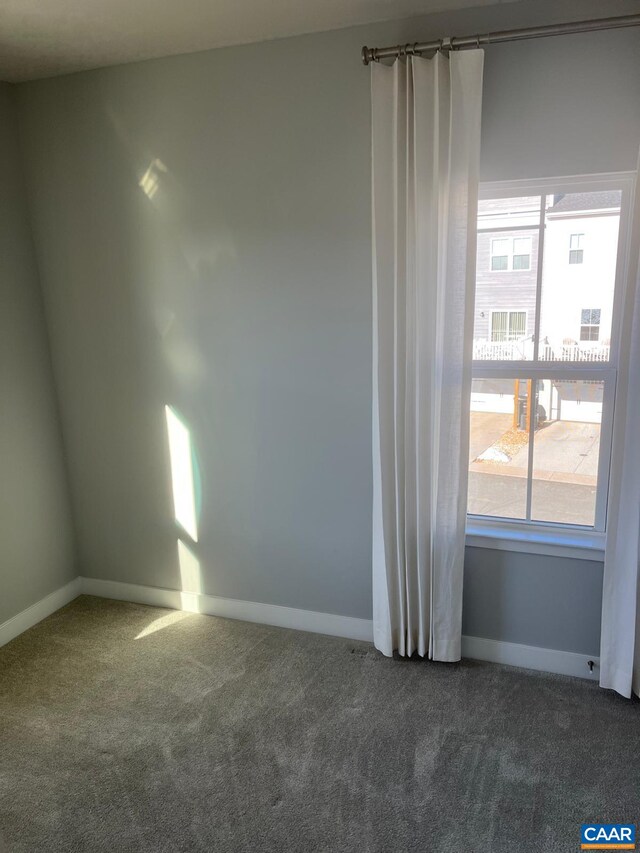 empty room with baseboards and dark carpet