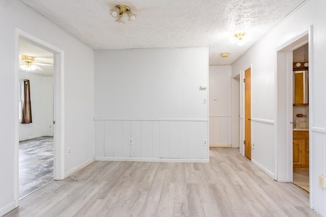 1627 Barbershop Rd, Edinburg, VA 22824 - empty room featuring a wainscoted wall, a textured ceiling, light wood-style flooring, and a ceiling fan