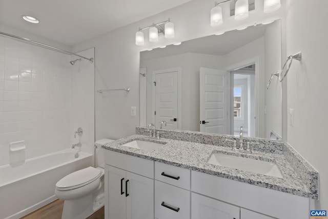 bathroom featuring toilet, wood finished floors, double vanity, bathtub / shower combination, and recessed lighting