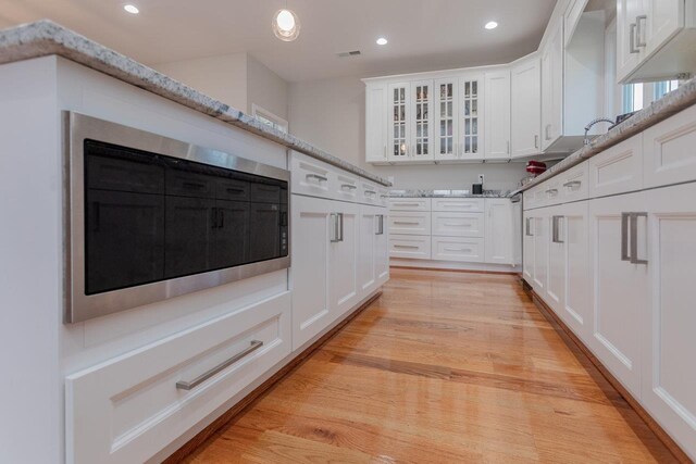 kitchen featuring white cabinetry, light stone counters, and light hardwood / wood-style flooring