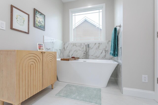 bathroom with tile walls, a bathtub, and tile patterned floors