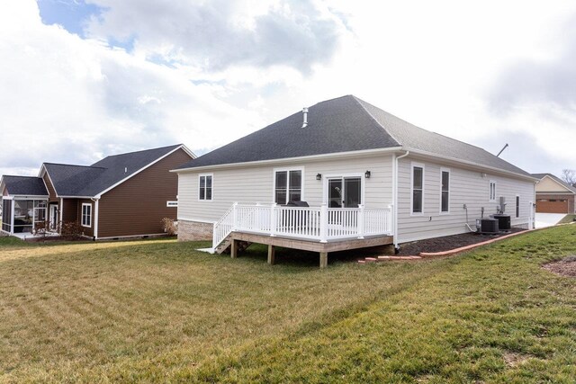 rear view of property featuring central AC unit, a deck, and a lawn