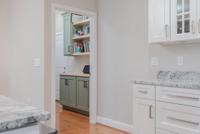 bar featuring white cabinetry, light stone counters, and light wood-type flooring