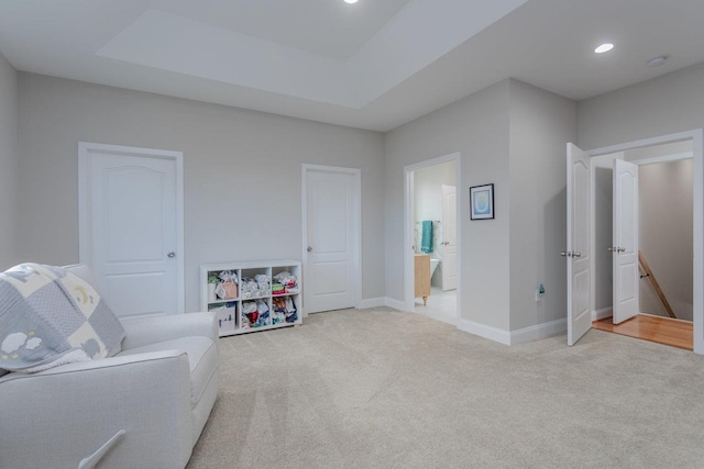 living area featuring a tray ceiling and light colored carpet