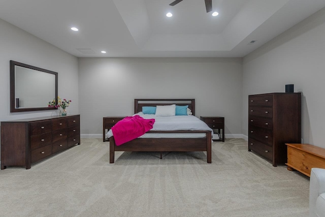 bedroom featuring a raised ceiling and light carpet