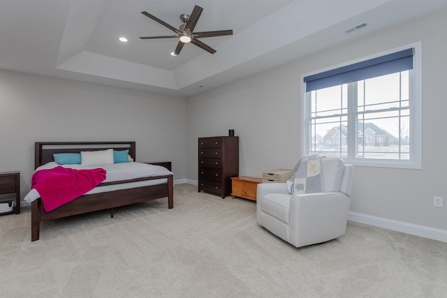 bedroom featuring a tray ceiling, light colored carpet, and ceiling fan