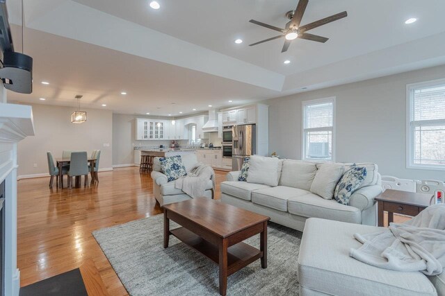 living room with ceiling fan, a healthy amount of sunlight, and light wood-type flooring