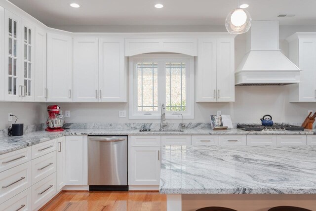 kitchen featuring sink, custom exhaust hood, white cabinetry, decorative light fixtures, and stainless steel appliances