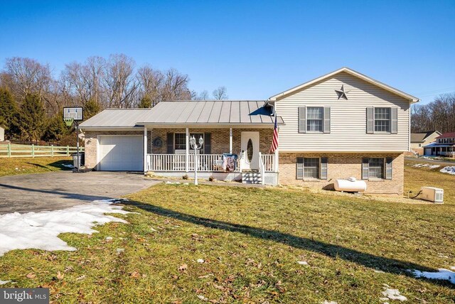 tri-level home featuring a garage, covered porch, and a front lawn