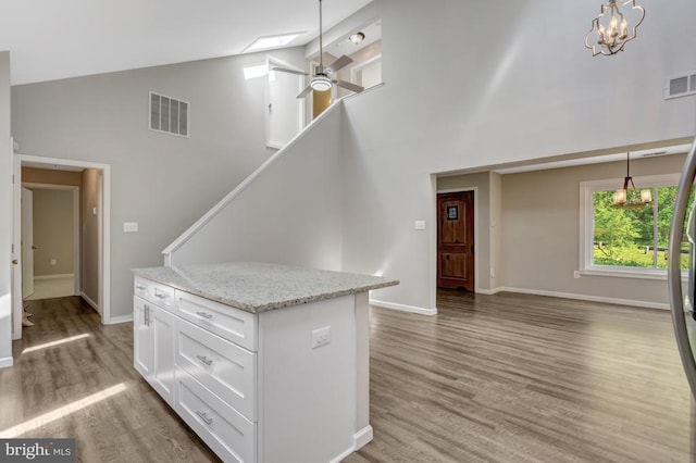  - interior space with baseboards, visible vents, ceiling fan with notable chandelier, high vaulted ceiling, and light wood-style floors