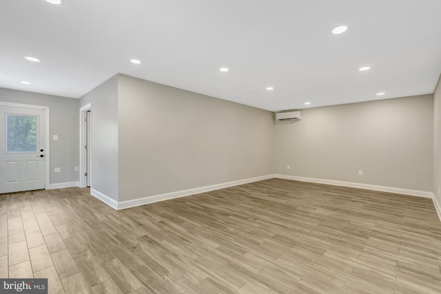  - below grade area featuring an AC wall unit, baseboards, light wood-type flooring, and recessed lighting