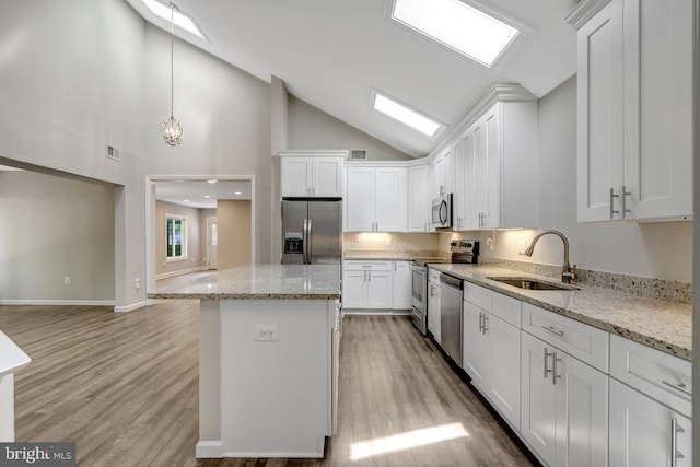  - kitchen featuring a sink, stainless steel appliances, white cabinetry, and a kitchen island
