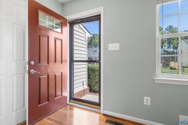 foyer with light wood finished floors, a wealth of natural light, baseboards, and visible vents
