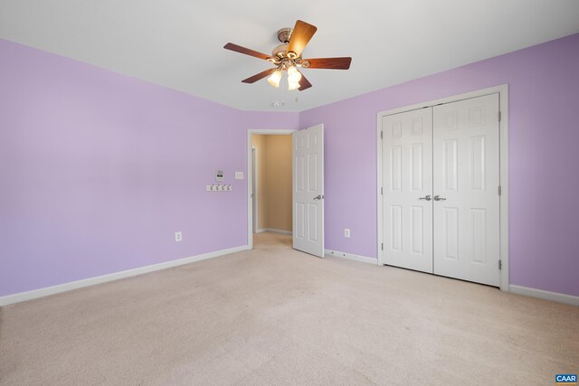 unfurnished bedroom featuring light colored carpet, a closet, and baseboards