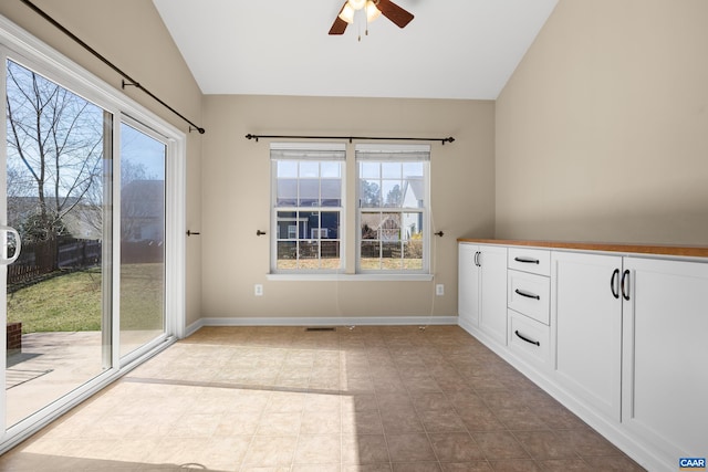 interior space with baseboards, visible vents, ceiling fan, and vaulted ceiling