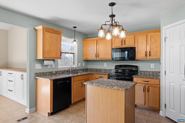 kitchen featuring a center island, a sink, dark stone counters, visible vents, and black appliances