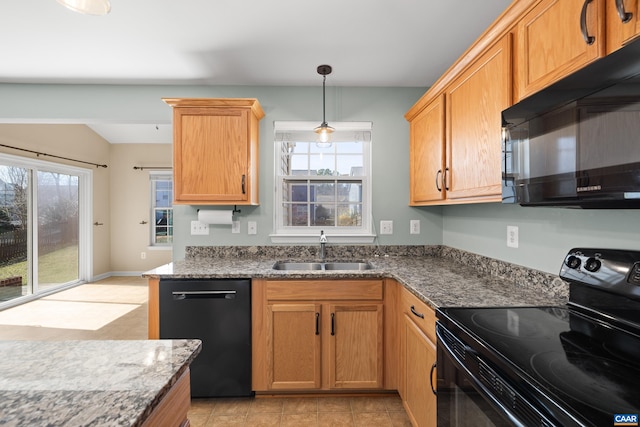 kitchen featuring dark stone counters, plenty of natural light, black appliances, and a sink