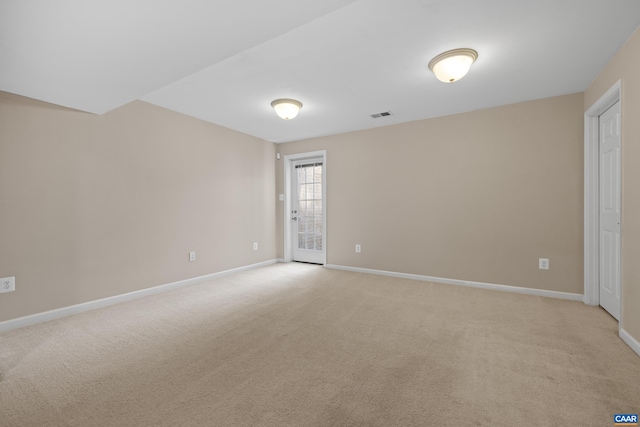 spare room featuring baseboards, light carpet, and visible vents