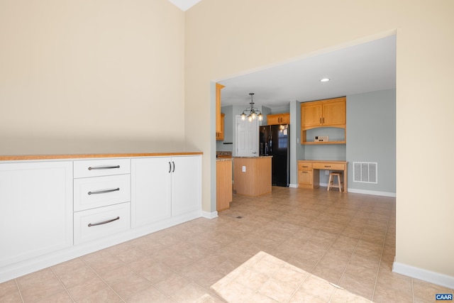 kitchen featuring baseboards, visible vents, black fridge with ice dispenser, a chandelier, and a kitchen island