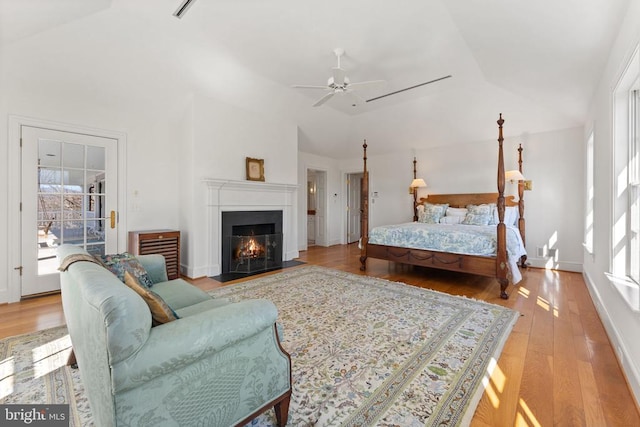  - bedroom with lofted ceiling, light wood-style flooring, a fireplace with flush hearth, and ceiling fan
