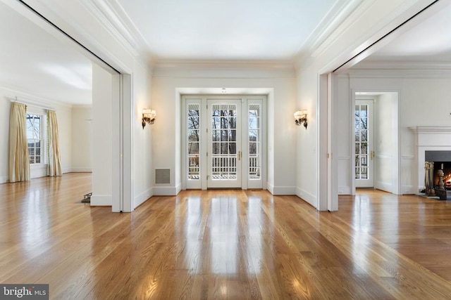  - entryway featuring a warm lit fireplace, wood finished floors, ornamental molding, and baseboards