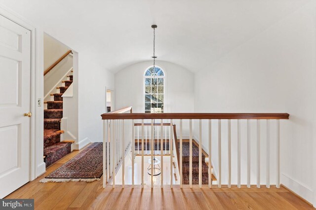  - corridor featuring wood finished floors, lofted ceiling, and stairs
