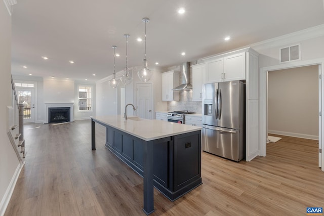 403 Bayberry Ln, Zion Crossroads, VA 22942 - kitchen featuring appliances with stainless steel finishes, wall chimney exhaust hood, white cabinetry, light wood finished floors, and backsplash