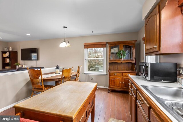 11404 Warner Dr, Fredericksburg, VA 22407 - kitchen featuring stainless steel microwave, brown cabinets, light wood-style floors, a sink, and pendant lighting