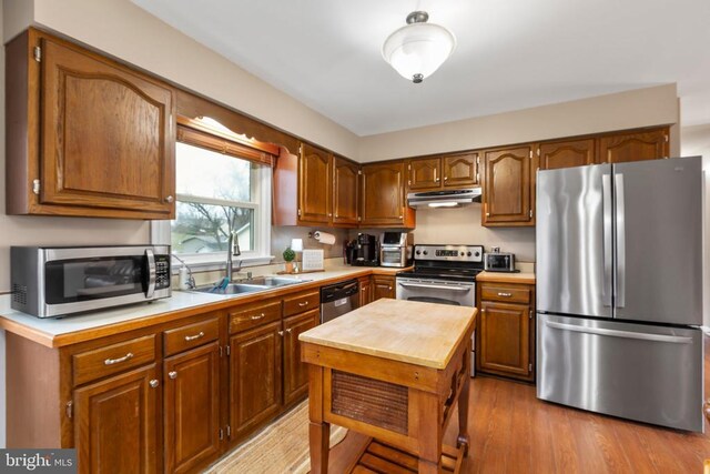 11404 Warner Dr, Fredericksburg, VA 22407 - kitchen featuring appliances with stainless steel finishes, a sink, under cabinet range hood, light countertops, and brown cabinetry