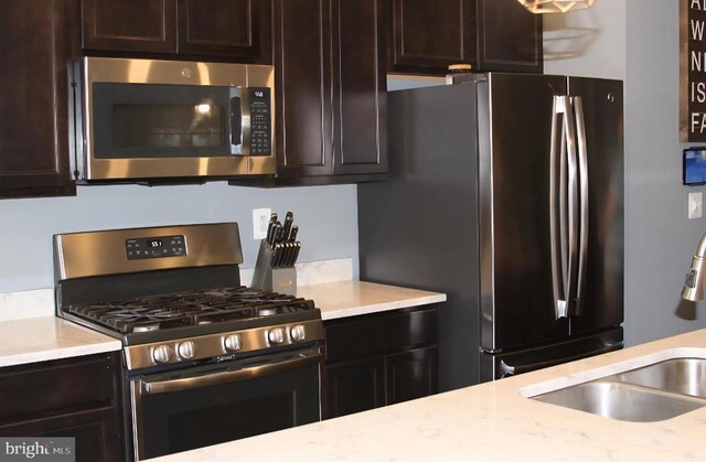 2437 Drake Ln, Fredericksburg, VA 22408 - kitchen featuring stainless steel appliances, a sink, dark brown cabinetry, and light stone countertops