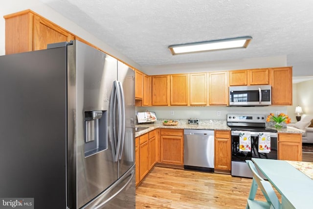 2912 Broyhill Ct, Fredericksburg, VA 22408 - kitchen with stainless steel appliances, light wood-type flooring, a textured ceiling, and light stone counters
