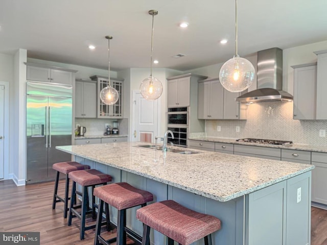 8525 Laroque Run Dr, Fredericksburg, VA 22407 - kitchen with stainless steel appliances, wall chimney exhaust hood, gray cabinetry, tasteful backsplash, and wood finished floors