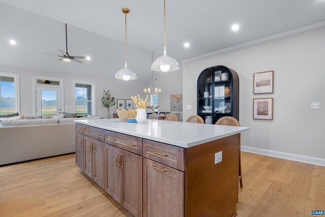 kitchen with light wood-style flooring, a kitchen breakfast bar, open floor plan, ceiling fan, and a kitchen island