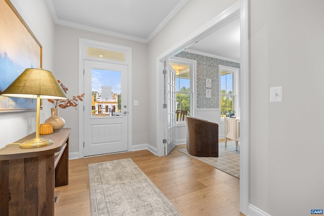 foyer entrance featuring crown molding, baseboards, and light wood-type flooring