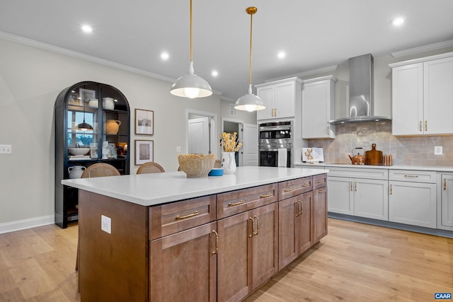 kitchen featuring recessed lighting, a center island, crown molding, wall chimney range hood, and double oven