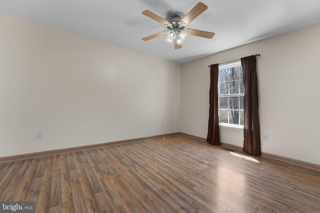 empty room featuring ceiling fan, wood finished floors, and baseboards