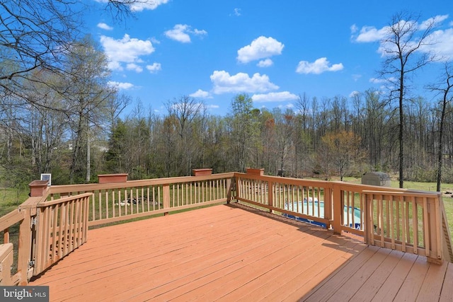 wooden terrace featuring a shed, an outbuilding, and a covered pool