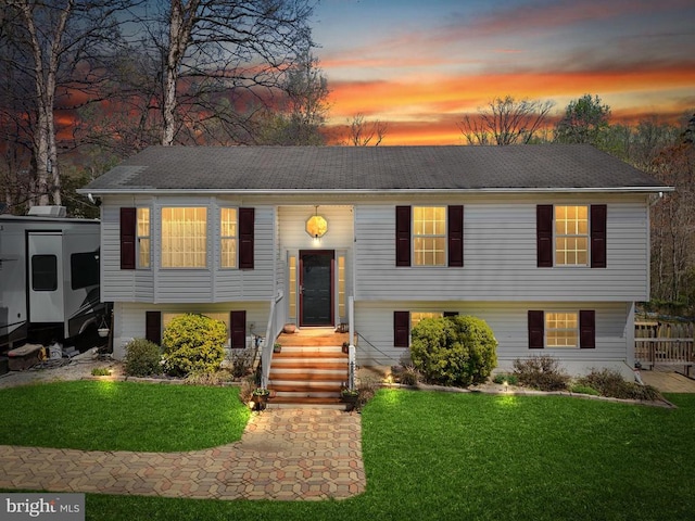 split foyer home with a yard and roof with shingles