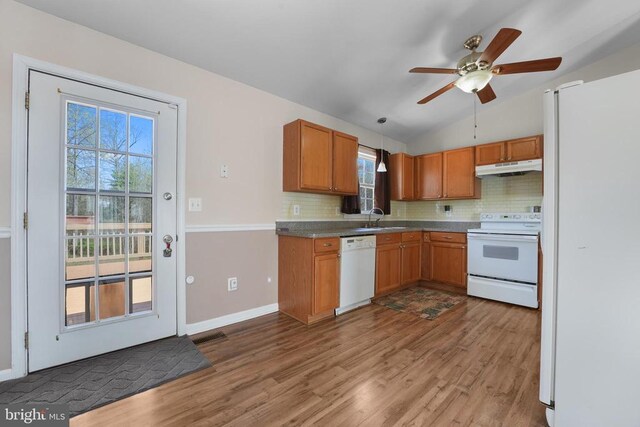 kitchen with white appliances, a sink, under cabinet range hood, wood finished floors, and backsplash
