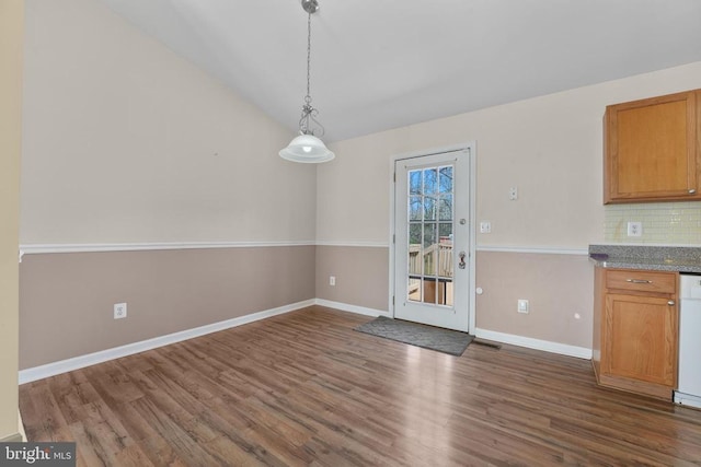 unfurnished dining area featuring dark wood-type flooring, baseboards, and vaulted ceiling