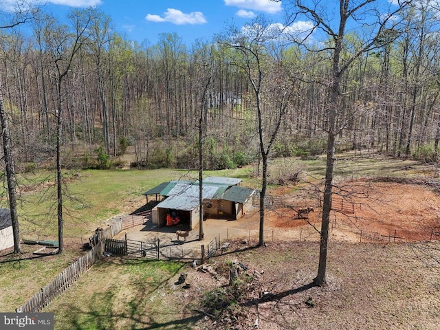 view of yard with an outbuilding, an exterior structure, fence, and a wooded view