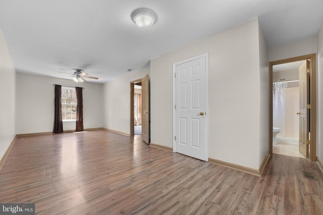 unfurnished living room with ceiling fan, wood finished floors, and baseboards