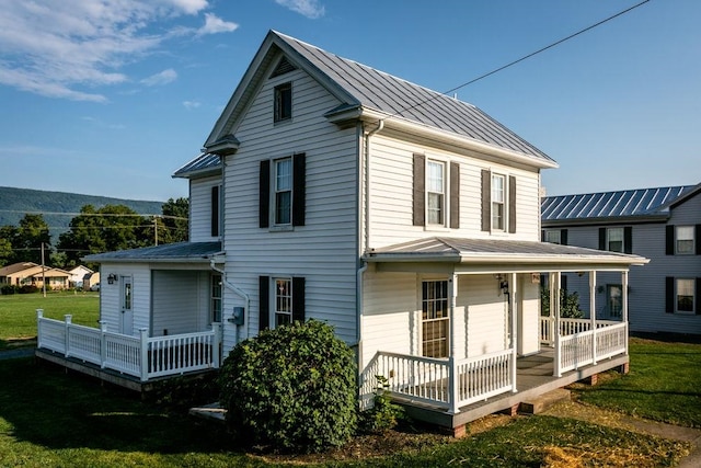 back of house featuring a yard, metal roof, a standing seam roof, and covered porch