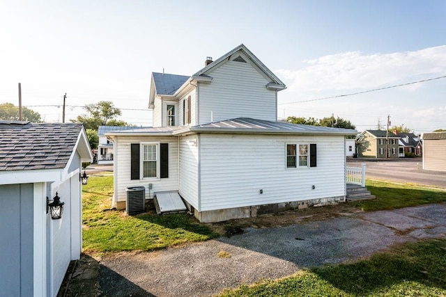 rear view of property featuring metal roof, a standing seam roof, and central AC