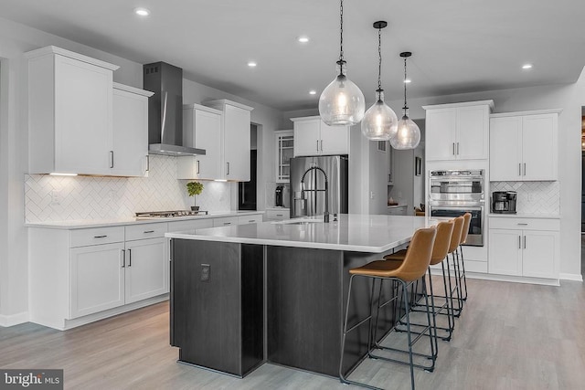 10115 Premier St, Fredericksburg, VA 22408 - kitchen featuring wall chimney range hood, backsplash, light wood-style floors, stainless steel appliances, and recessed lighting