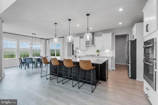 10115 Premier St, Fredericksburg, VA 22408 - kitchen with stainless steel appliances, light countertops, an island with sink, wall chimney range hood, and decorative backsplash