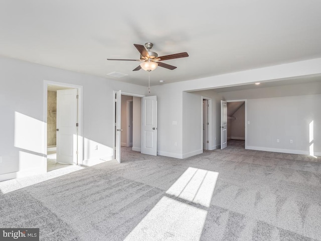 unfurnished bedroom with carpet, baseboards, ensuite bathroom, a walk in closet, and ceiling fan