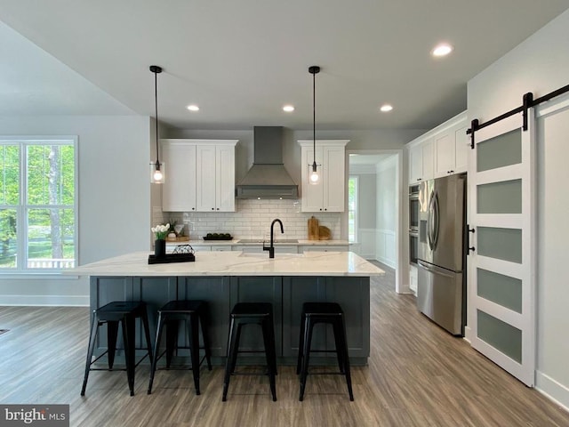 kitchen with custom exhaust hood, stainless steel appliances, wood finished floors, white cabinets, and recessed lighting