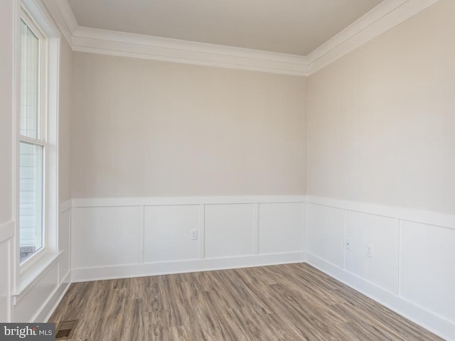 unfurnished room with ornamental molding, wood finished floors, a wainscoted wall, and a decorative wall